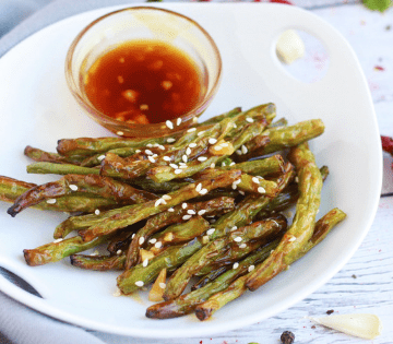 A plate of Air Fryer Green Beans and Chili Garlic Sauce