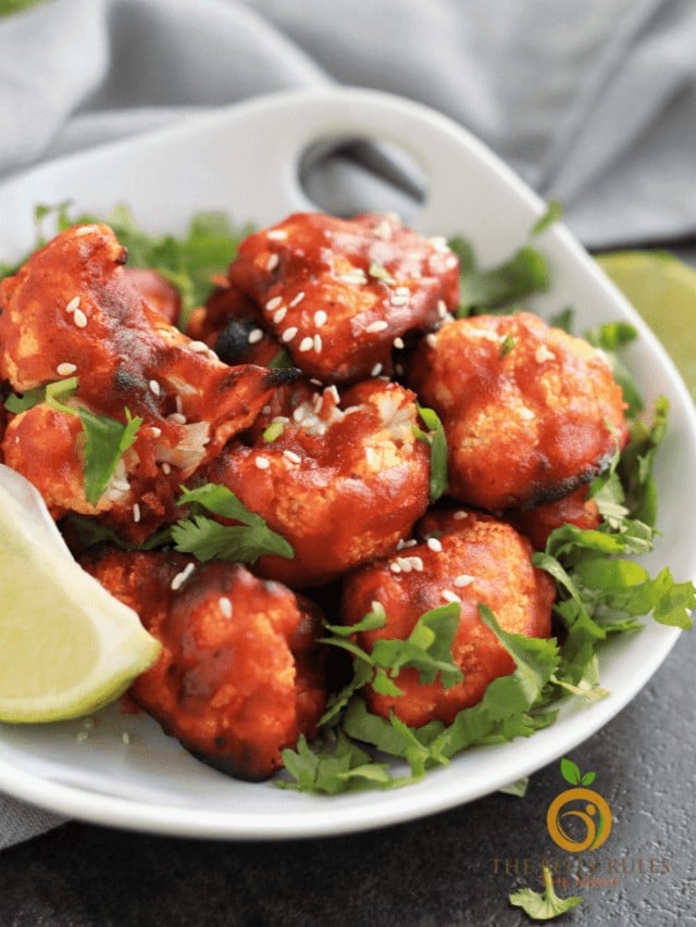 Crispy spicy chicken bites garnished with cilantro and lime wedge.