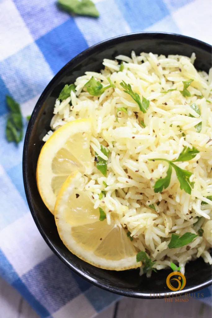 Lemon rice cooked with herbs in a bowl with lemon wedges
