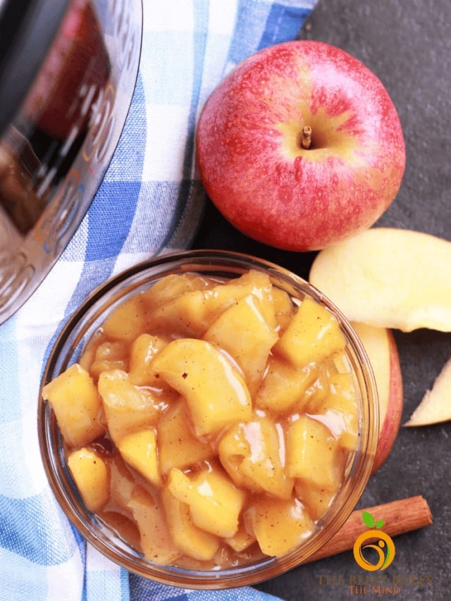 Fresh apple and mango fruit salad in a glass bowl with whole apple and sliced mango.