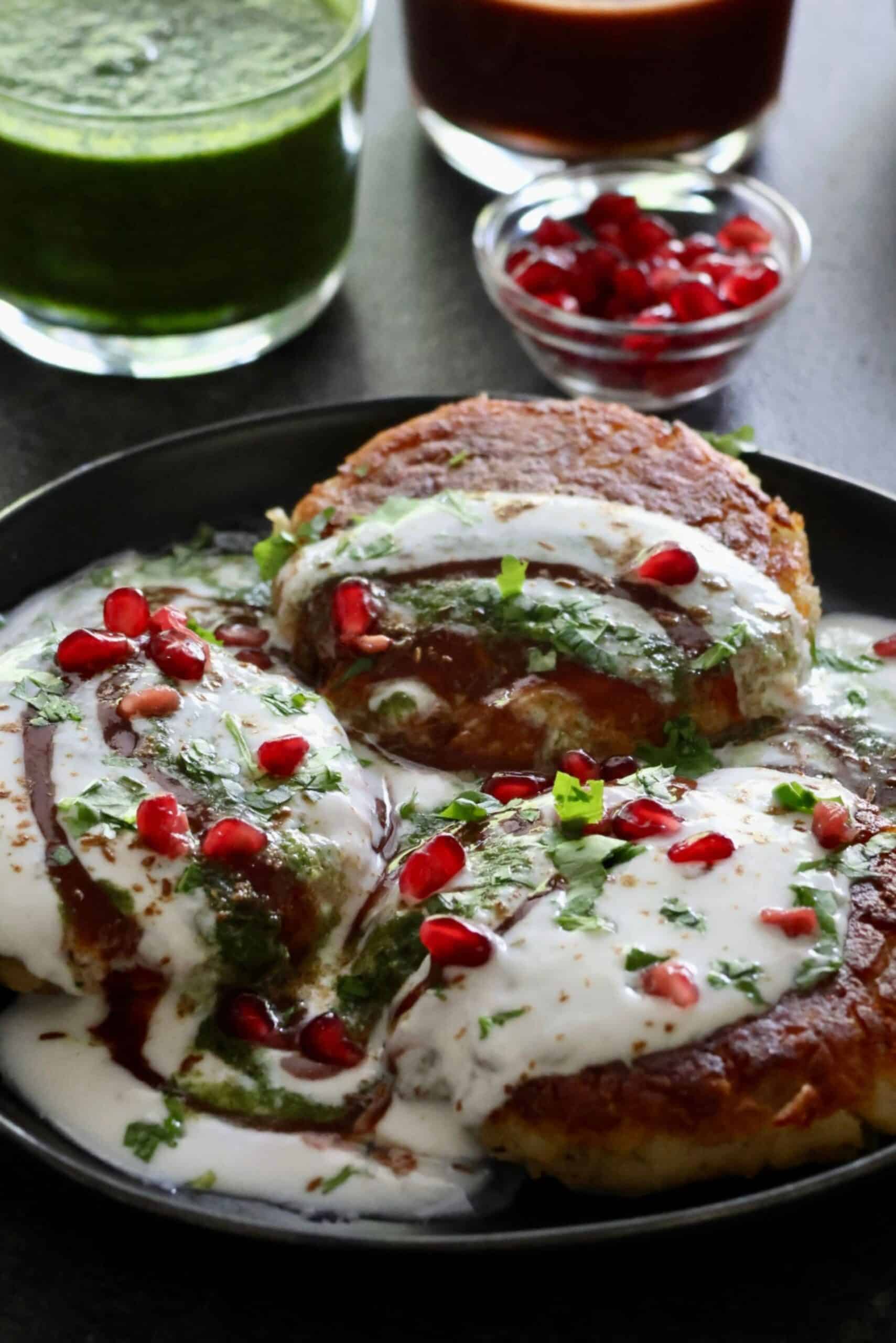 Aloo Tikki Chaat with Channa Dal stuffing, topped with yogurt, pomegranate seeds, and green chutney,.