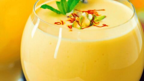 Delicious thick mango lassi in a glass with garnishes, perfect for summer drinks.