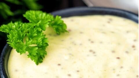 Spicy mustard aioli sauce served in a bowl with fresh parsley garnish.