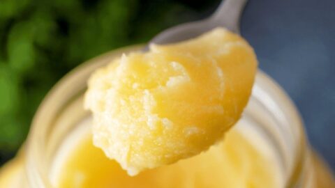 Homemade ghee and clarified butter in a jar with a spoonful ready to serve.