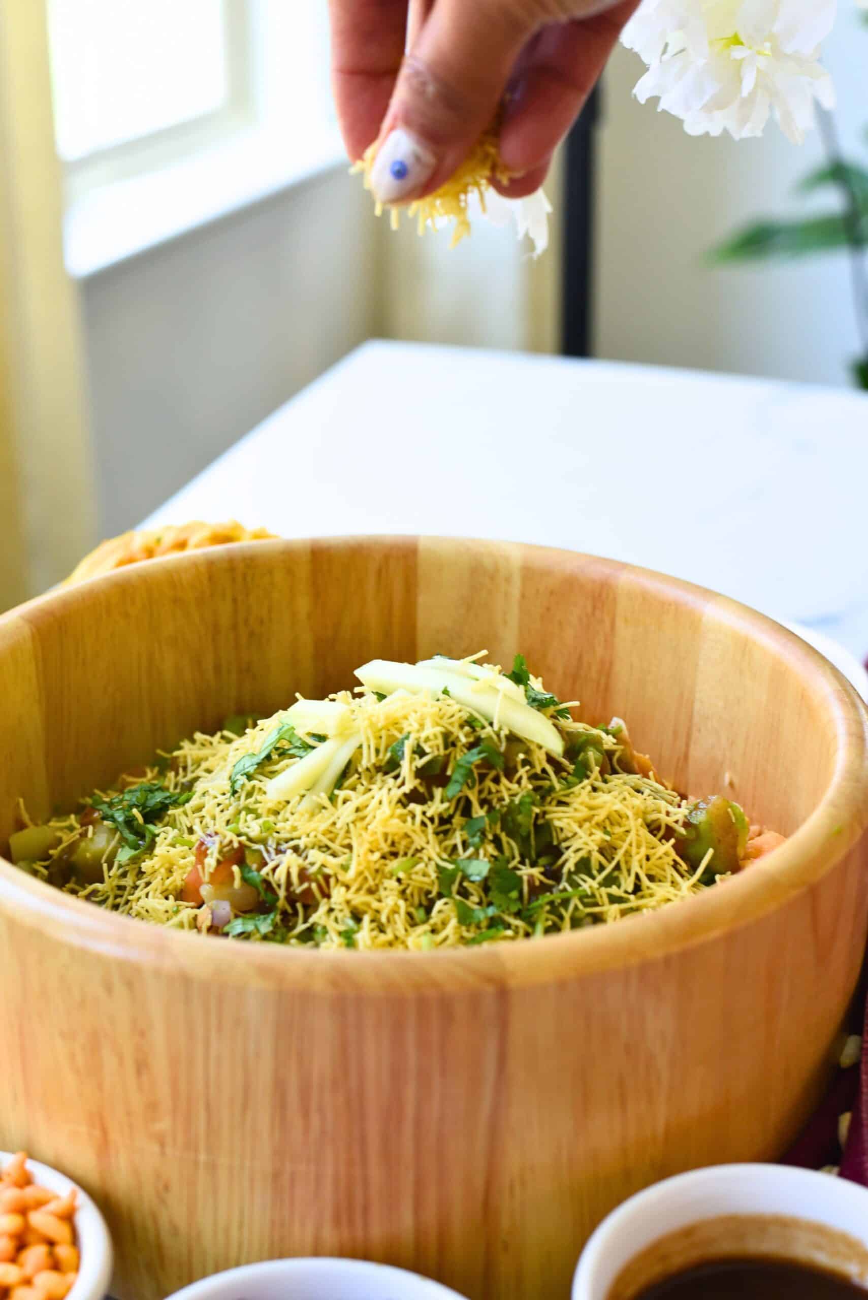 Delicious Bhel Puri served in a wooden bowl, topped with sev and fresh herbs.