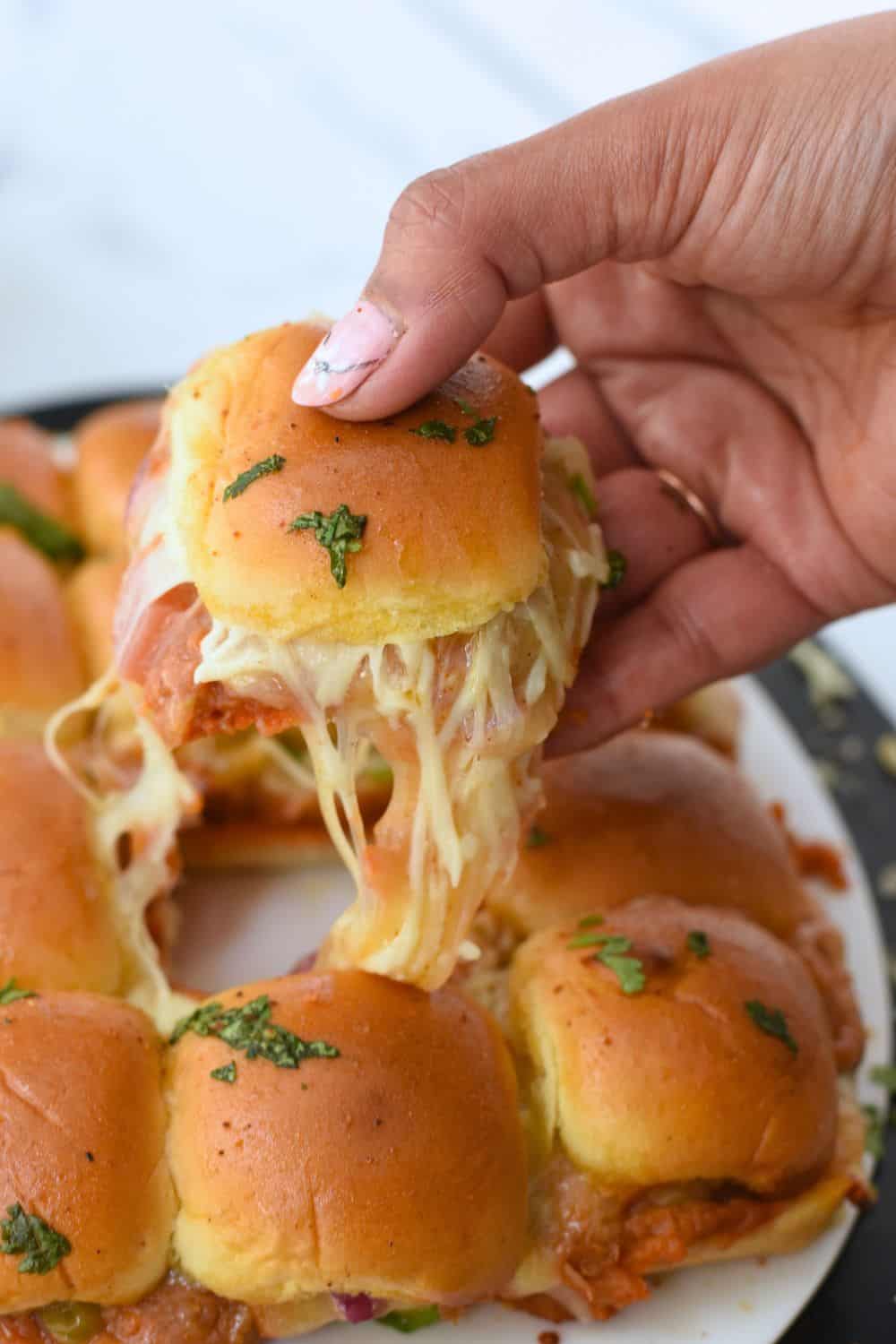 Delicious Pav Bhaji sliders topped with melted cheese and fresh herbs, perfect for snack or party appetizers