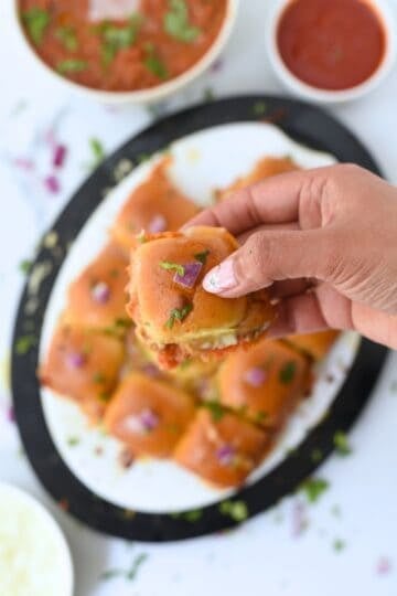 Close-up of Pav Bhaji sliders garnished with herbs and edible flowers.