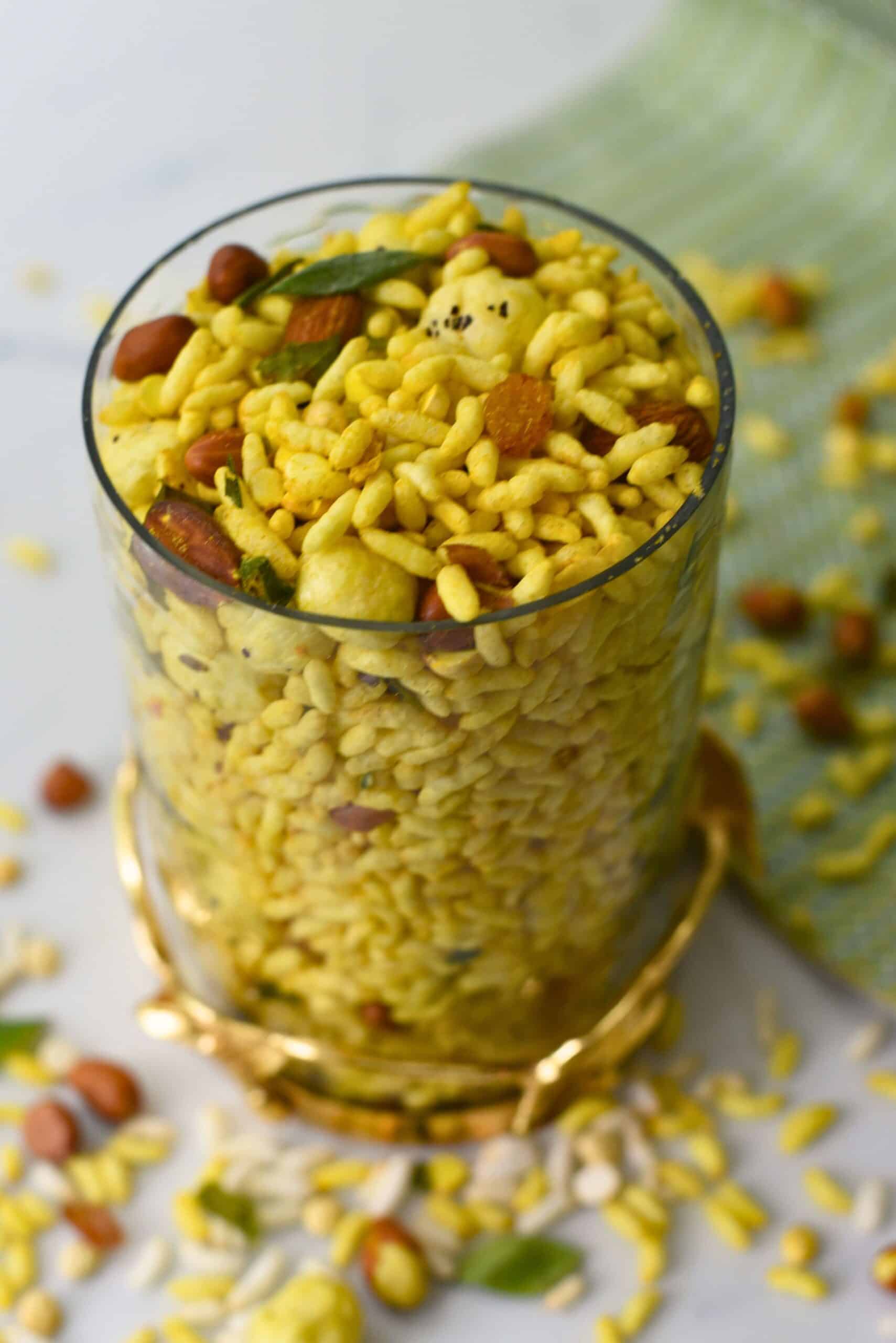 Delicious spicy murmura chivda served in a glass with nuts and herbs, perfect for a healthy snack.