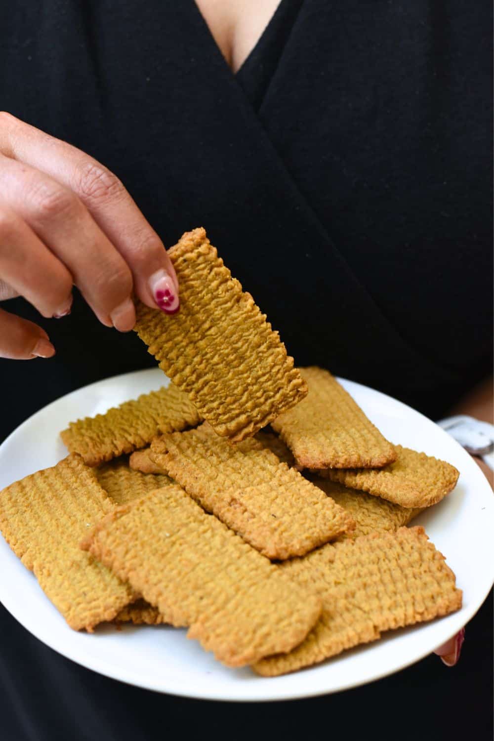 Close-up of crispy, golden Punjabi Atta Biscuits on a white plate.