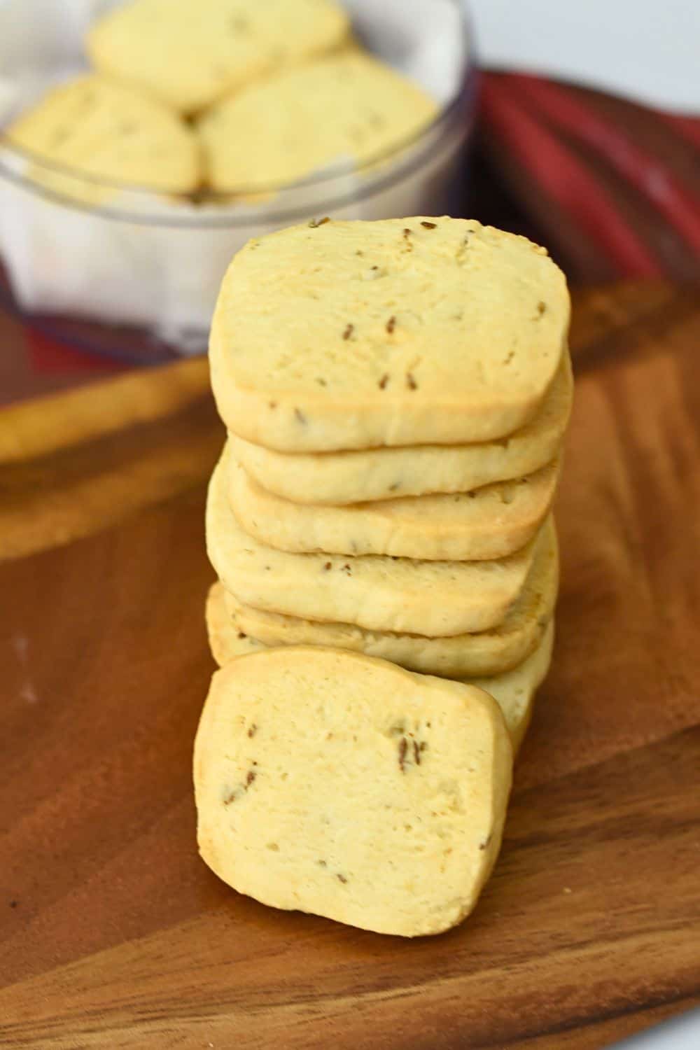 Stack of homemade jeera biscuits on wooden board for tea time.