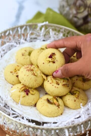 Close-up of eggless Nankhatai cookies garnished with pistachios and saffron.